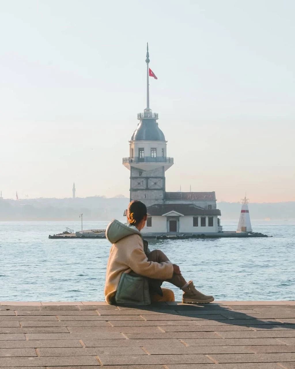 Woman sitting by the Bosphorus facing the Maiden's Tower in Istanbul